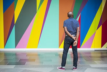 Artist Odili Donald Odita surveys the completed wall painting, "Shadow and Light (For Julian Francis Abele)." Photo by J Caldwell.