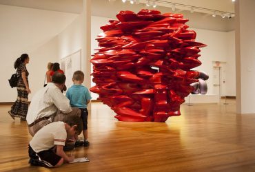 On a free Family Day, visitors check out a large, red sculpture made of wood by Tony Cragg. Photo by J Caldwell.