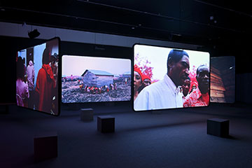 Installation view of Richard Mosse: The Enclave. The six-channel video was presented in a large pavilion with black walls, ceiling and floor.