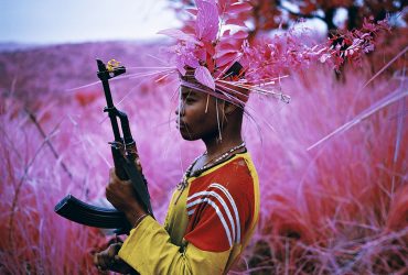 Mosse spent the last several years photographing the war-ravaged land and people of Central Africa using a discontinued infrared film developed by the military to detect camouflaged targets. In this still image, a soldier stands in profile holding a rifle pointed up.