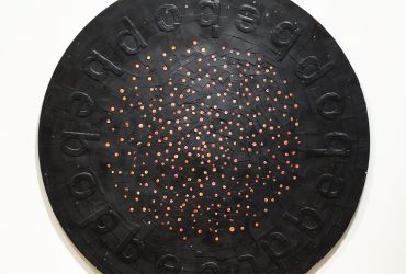 In this work, Ward uses basketball trading cards to draw a connection between sports, entertainment, and African American culture. The players have been blacked out, leaving only the balls on each card exposed, floating like celestial stars in the night sky. The word “bebop” embossed around the outer rim of the work refers to the fast tempo style of jazz made popular by Dizzy Gillespie and Charlie Parker, which is improvisational like the game of basketball. “Bebop,” when read aloud, has an almost onomatopoeia-like association with a ball bouncing. The work’s round shape brings to mind a vinyl record, a protective shield, or even a divination tray, used in Yoruba cosmology in West Africa. These characteristics suggest a reading of music and sports as “religions” that help us make sense of our place in the world.