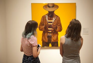 Visitors enjoy a painting by Barkley L. Hendricks, Down Home Taste, part of the exhibition Southern Accent: Seeking the American South in Contemporary Art. Photo by J Caldwell.