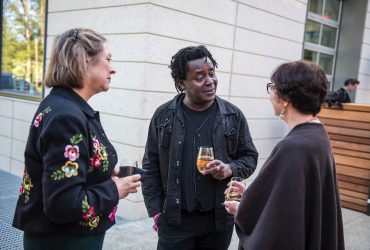 Gallery Guide Ruth Caccavale (left) and Conservator Ruth Cox (right) speak with artist John Akomfrah (center) at the Rubenstein Arts Center