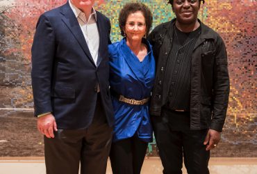 (Left to Right) David Haemisegger and his wife Nancy Nasher pose with artist John Akomfrah in front of Charles Gaines's work, Numbers and Trees, Central Park, Series I, Tree #9.