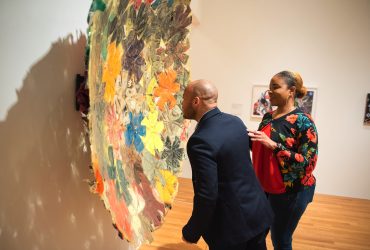 Two visitors admire "Bronx Fitted" by artist Kevin Beasley, part of "Solidary & Solitary"