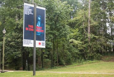 A RESIST COVID / TAKE 6! street pole banner at the Nasher Museum, facing Campus Drive. Courtesy of Carrie Mae Weems. Photo by J Caldwell.