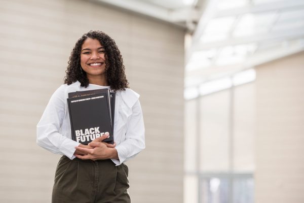 Adria Gunter, Curatorial Assistant at the Nasher Museum stands in the Nasher Museum's Great Hall with a selection of books