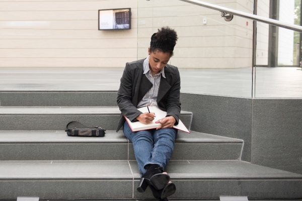 Briana Benkin, Nasher intern, on the steps of the museum writing in her journal.