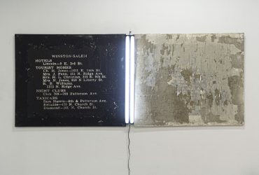 Johannes Barfield, In The Bilge Again, 2017. Concrete, asphalt, wheatpaste, and fluorescent lamp; 48 x 120 x 2 inches (121.9 x 304.8 x 5.08 cm). © Johannes Barfield. Image courtesy of the artist.