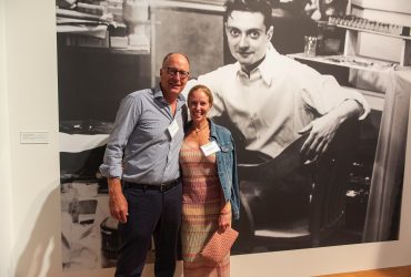 Nasher Museum Board of Advisors member Jason Rubell and his wife Michelle strike a pose in front of a wall mural of the young Roy Lichtenstein