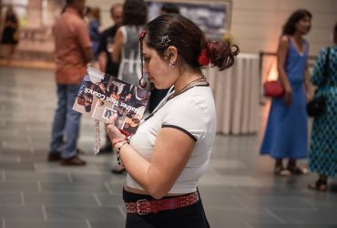 A teen visitor in the museum's great hall holds a flyer for our Nasher Teen Council