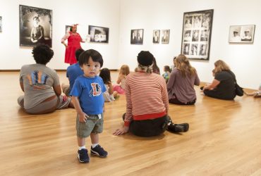 A very young person in a Durham Bulls t-shirt is part of the group of visitors at our bilingual story time