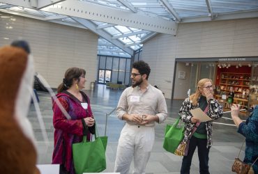 two pairs of people speaking to each other in the great hall of the museum